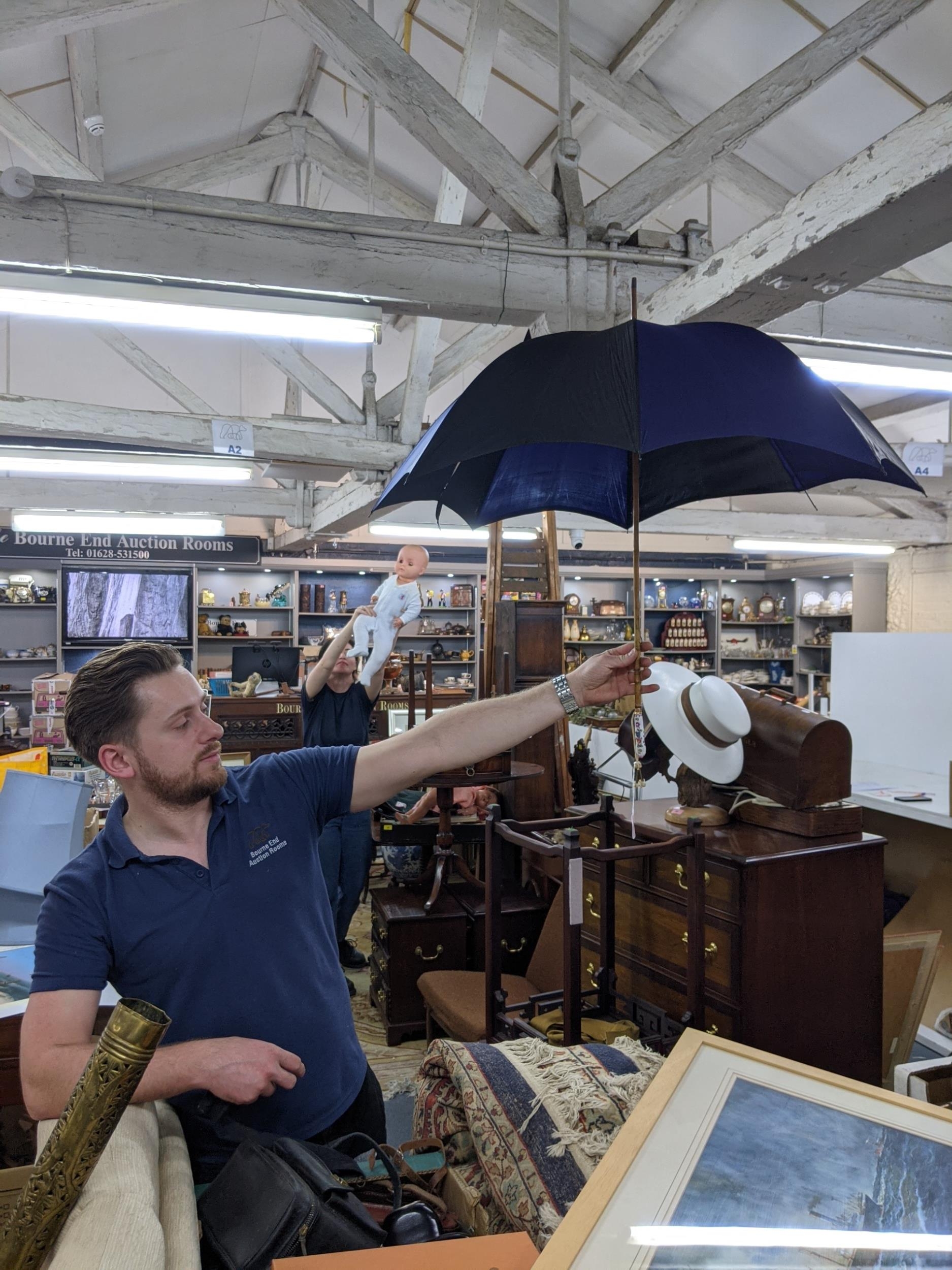 A mid 20th Century cane handled umbrella in black and navy with painted porcelain handle and