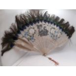 An early 20th Century Japanese fan having painted white feather wands A/F with peacock feather