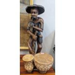 An African style wooden sculpture of a gentleman smoking a pipe 73cmh and a Moroccan clay drum Tom-