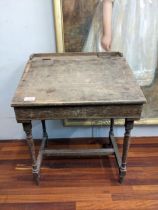 An early/mid 20th century child's desk with a hinged top, raised on tapered legs, united by a