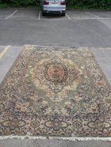 A traditional Persian style handwoven rug with central floral medallion on a green ground,