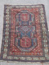 A Kazak rug decorated with symmetrical abstract motifs surrounded by quartered coloured geometric