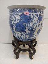 A modern Chinese fishbowl decorated in blue and white with exotic birds and flowers, on a wooden