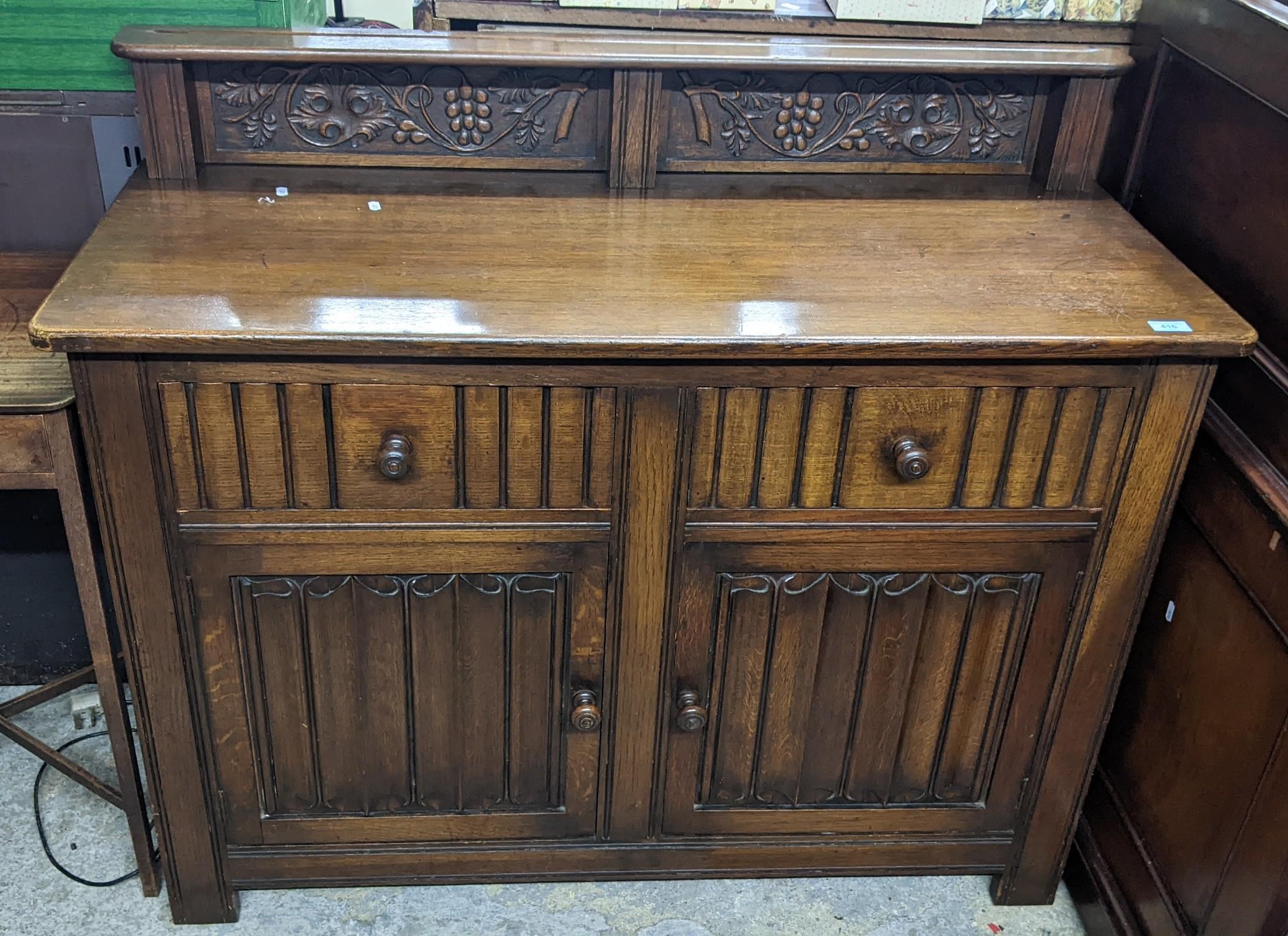 An early to mid oak linenfold sideboard, extended back with two panels of grape and vine leaf carved