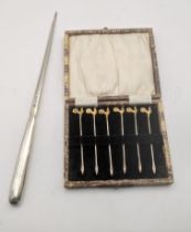 Silver to include six cocktail sticks in a fitted case, hallmarked London 1928, along with a meat