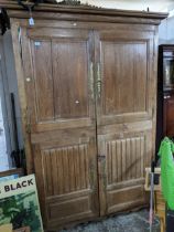 An 18th century oak armoire, twin panelled and carved doors with brass escutcheons, shaped apron and