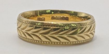 An 18ct gold wedding band having a repeating engraved pattern 6.4g Location: If there is no
