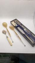A pair of horn and silver salad servers, silver handled carving set and a jam spoon Location: If