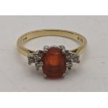 An 18ct gold ring set with diamonds to the shoulders and a central amber coloured stone 2.9g