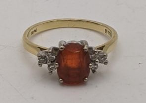An 18ct gold ring set with diamonds to the shoulders and a central amber coloured stone 2.9g