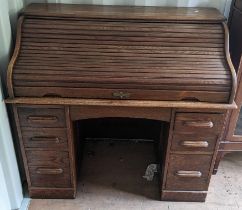 An early/mid 20th century oak roll top desk having a fitted interior, drawer below and drawer