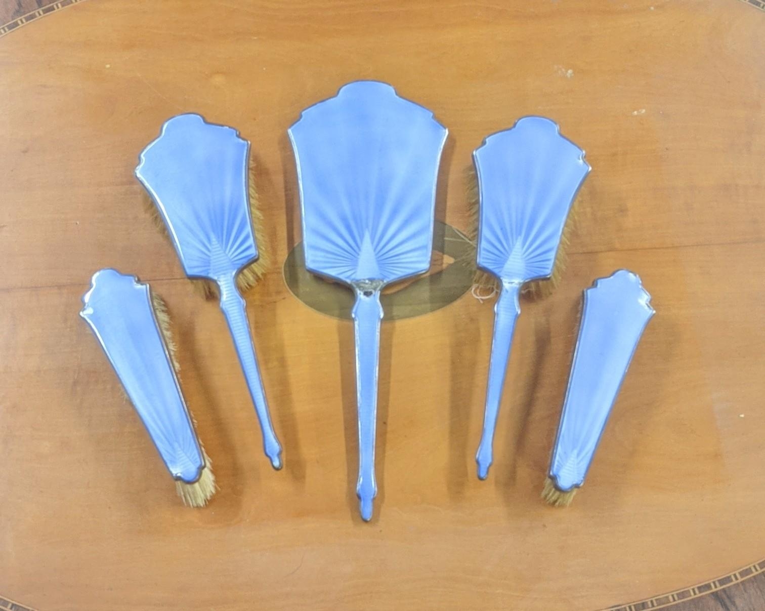 A set of five silver and enamelled dressing table items, to include a hand mirror and 4 brushes