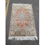 A Turkish silk rug decorated with a central motif surrounded by flowers and foliage on an orange