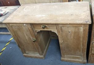 A 19th century pine kneehole desk having a single drawer flanked by two cupboard doors 76cm h x