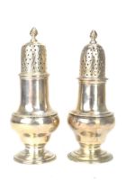 A matched pair of George III silver shakers, one hallmarked London 1761 and the other London 1773,