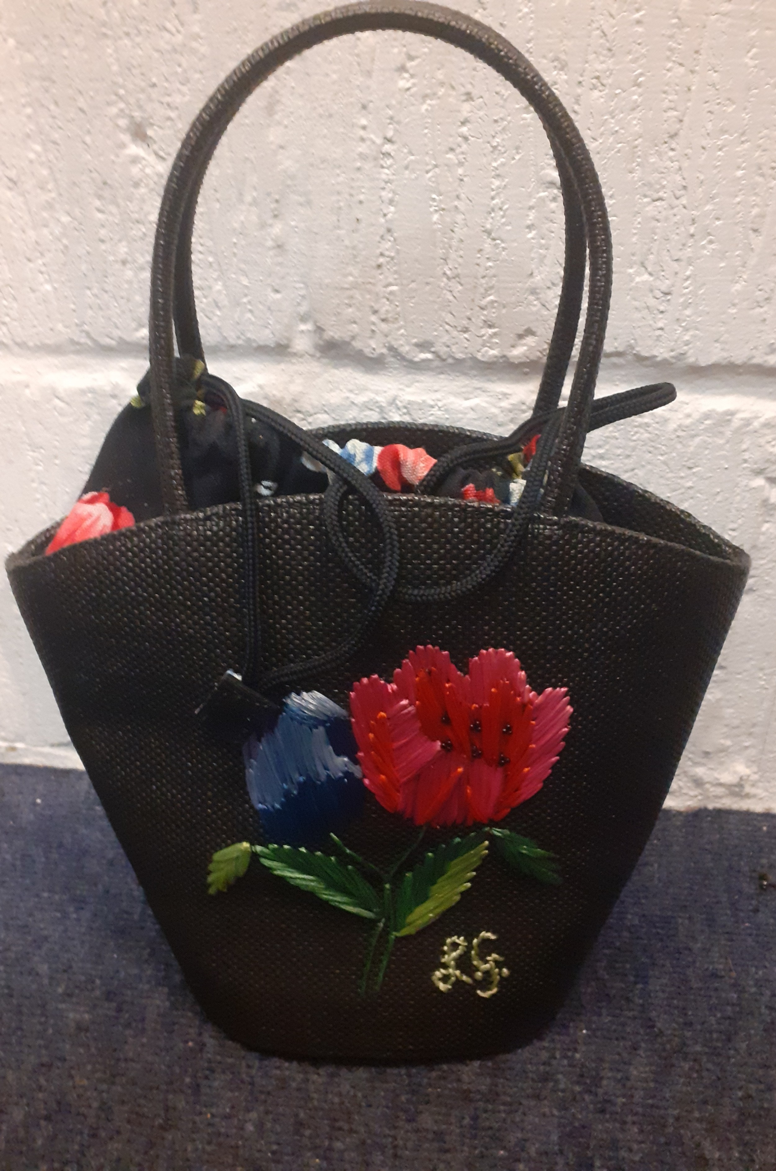 Lulu Guinness- An embroidered black straw bag with floral cloth lining having a drawstring