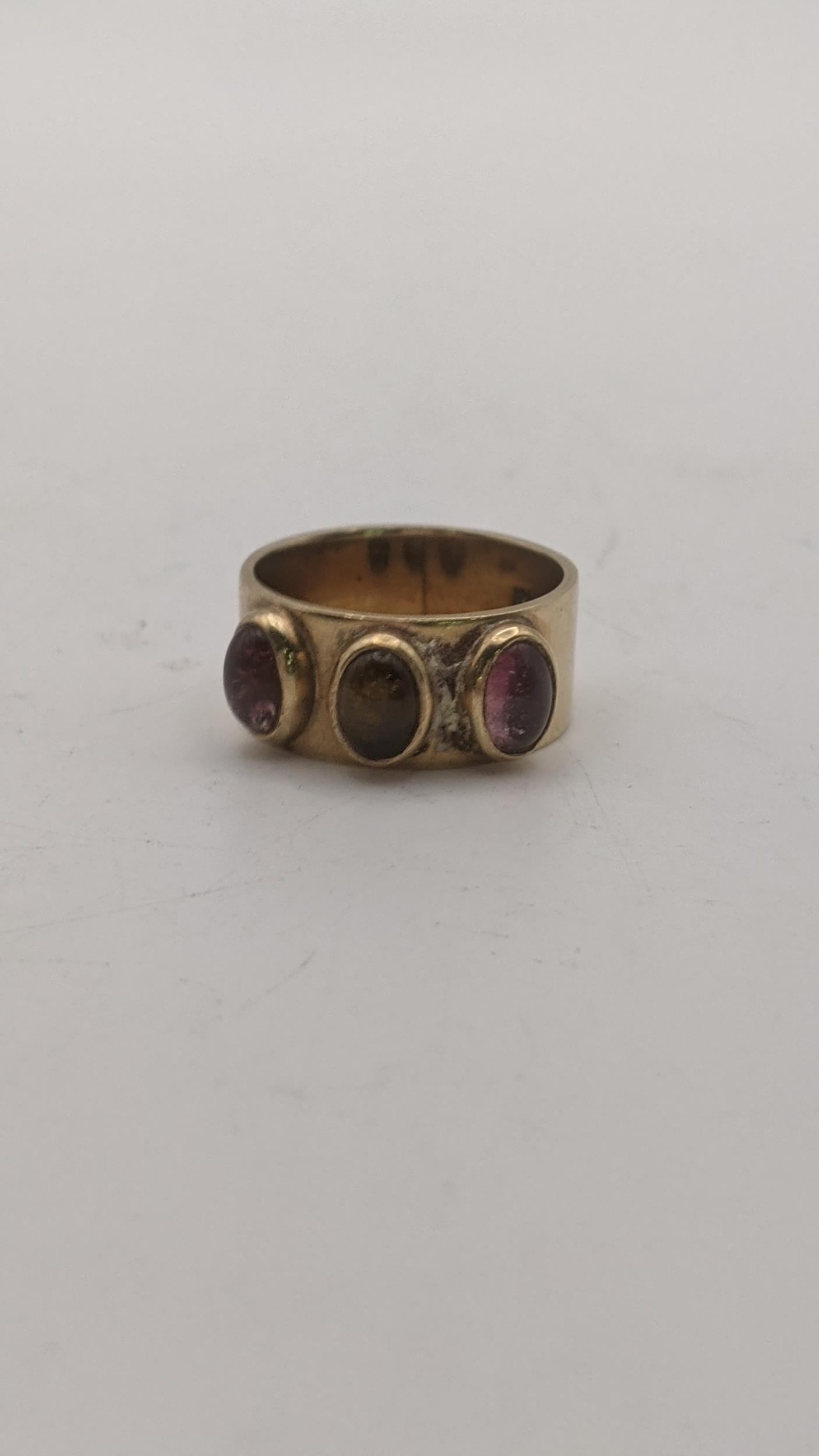 A 9ct gold ring set with a central brown cabochon, flanked by two purple cabochons, 7g Location: