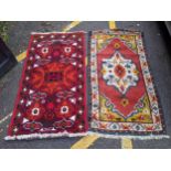 Two rugs, one with a central floral decoration in a white emblem with white repeating border and