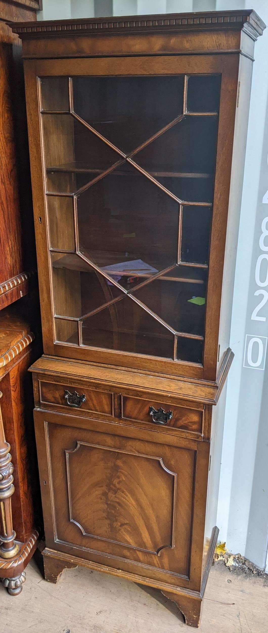 A reproduction mahogany cabinet having a glazed door above drawers and cupboard door, 173cm h x 58cm