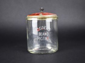 An Ogden's Beano Pigtail Glass Advertising Pot with Painted Tin Plate Lid, 17cms High