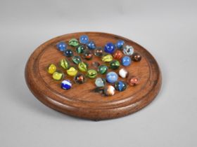 An Edwardian Circular Wooden Solitaire Board and Collection of Marbles, 21cms Diameter