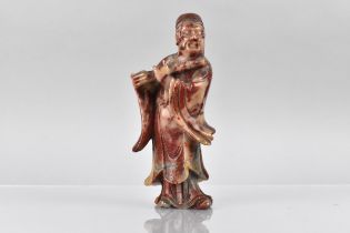 A Chinese Qing Dynasty Carved Soapstone Figure of Carved Court Official Playing Pipe, Variegated