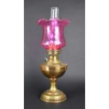 An Early 20th Century Brass Oil Lamp with Cranberry Glass Shade and Plain Glass Chimney, 57cms High