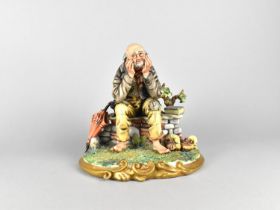 A Capodimonte Figure of a Tramp Seated on Stone Wall, 23cms High