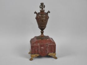 A French Patinated Spelter and Red Marble Clock Garniture in the Form of a Two Handled Vase, Four