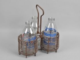 A Vintage Wire Two Bottle Milk Carrier with Three Decorated Milk Bottles