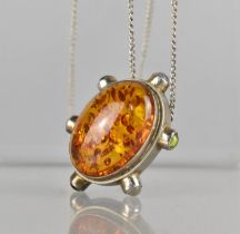 A Silver Mounted Pendant with Amber Cabochon Set Along with Three Small Peridot and Three