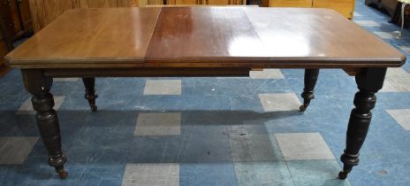 An Edwardian Mahogany Wind Out Rectangular Dining Table with Turned Supports and One Extra Leaf