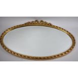 An Oval Gilt Framed Bevelled Glass Wall Mirror with Rose and Ribbon Finial, 72x48cm