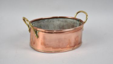 An Oval Copper Cooking Pan with Twin Brass Handles, 21cms Wide