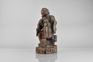 A Chinese Qing Dynasty Hardwood Carving of Deity Modelled Seated with Foot Upon Pine Cone