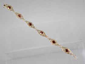 A 9ct Gold and Garnet Six Panel Bracelet, Each Panel with Oval Cut Stone Measuring 7.1mm by 5mm, Set