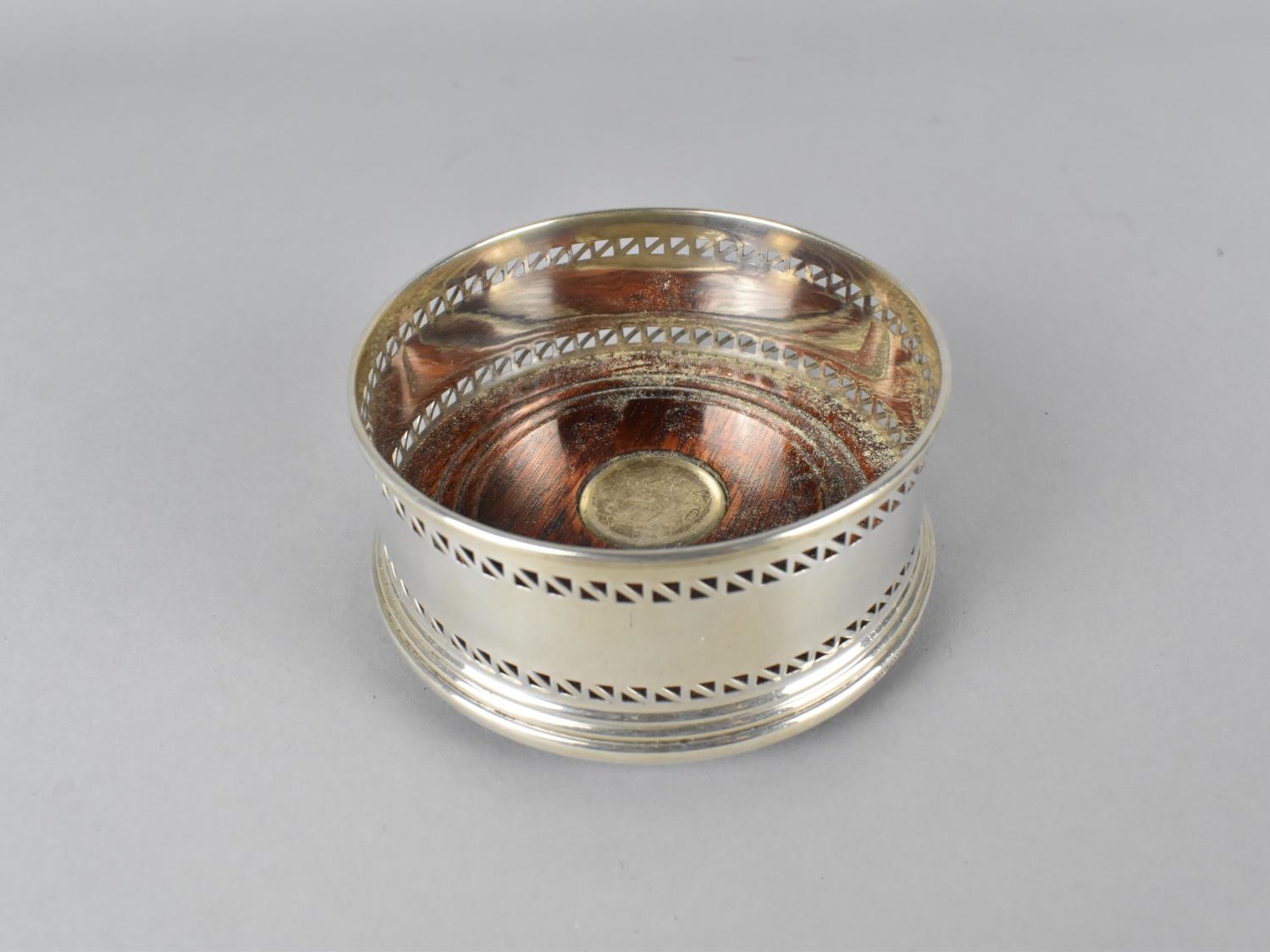 A Silver Bottle Coaster with Pierced Trim and Turned Wooden Base with Silver Mount, 9cm diameter