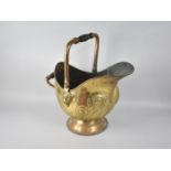 A Mid 20th Century Brass Helmet Shaped Coal Scuttle with Relief Decoration and Turned Wooden Handle,