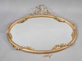 An Edwardian Oval Wall Hanging Gilt Framed Mirror with Floral Swag and Ribbon Decoration,