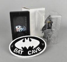 A Reproduction Cast Metal Oval Sign Bat Cave, Two Cased Dark Knight Medallions and a Batman Figure