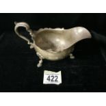 A STERLING SILVER SAUCEBOAT; SHEFFIELD 1923; SCROLL HANDLE; WAVY EDGE; ON THREE SHELL AND HOOF FEET;