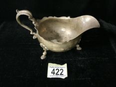 A STERLING SILVER SAUCEBOAT; SHEFFIELD 1923; SCROLL HANDLE; WAVY EDGE; ON THREE SHELL AND HOOF FEET;