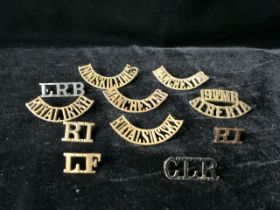 A QUANTITY OF MILITARY METAL SHOULDER TITLES; INCLUDING ROYAL IRISH, INNISKILLING, MANCHESTER AND