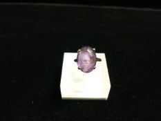 A 14 CARAT GOLD GEM MOUNTED DRESS RING, INCUSE STAMPED '14K', PURPLE OVAL STONE