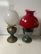 TWO VINTAGE OIL LAMPS; MILK WHITE AND RED GLASS SHADES