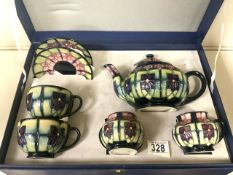 MOORCROFT: A CASED VIOLET PATTERN TEA SET AND PAIR OF CUPS AND SAUCERS DESIGNED BY SALLY TUFFIN