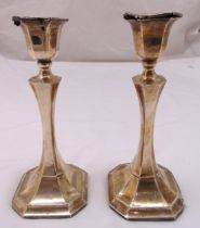 A pair of hallmarked silver table candlesticks of faceted cylindrical stems on raised octagonal
