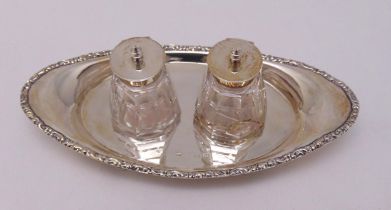 A hallmarked silver ink stand oval with scroll chased border on three pierced bracket feet with