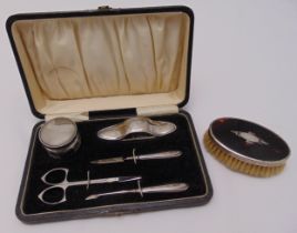 A cased hallmarked silver manicure set to include a glass bottle with silver cover, a nail buff, a