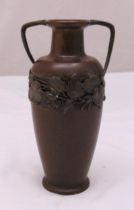 A bronze tapering cylindrical vase with two side handles the sides decorated with a floral band,